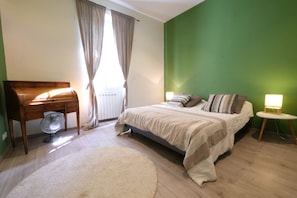 Un dormitorio con cama, mesita de noche, lámpara y ventilador.