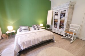 Une chambre à coucher comprenant un lit, des tables de chevet, une armoire et un fauteuil à bascule.