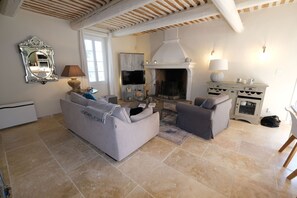 Una sala de estar con chimenea, un sofá, un televisor y un comedor.