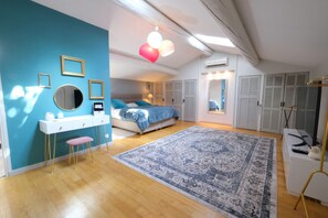 Une chambre à coucher avec un lit, des tables de chevet, une commode, un miroir et un mur bleu.