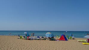 Una playa con tumbonas, sombrillas y una carpa.