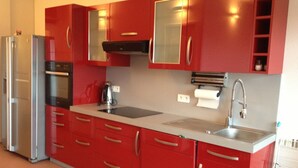 A modern kitchen with red cabinets, stainless steel appliances, and a white countertop. - AJACCIO Furnished apartment with breathtaking sea view, facing Marinella beach. (Ajaccio)