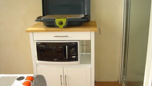 A compact kitchenette with a microwave and a small oven, a wooden countertop, and a cabinet. - AJACCIO Furnished apartment with breathtaking sea view, facing Marinella beach. (Ajaccio)