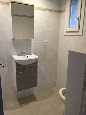 Ein Badezimmer mit einem weißen Waschbecken, einem Spiegel darüber und einer Toilette.