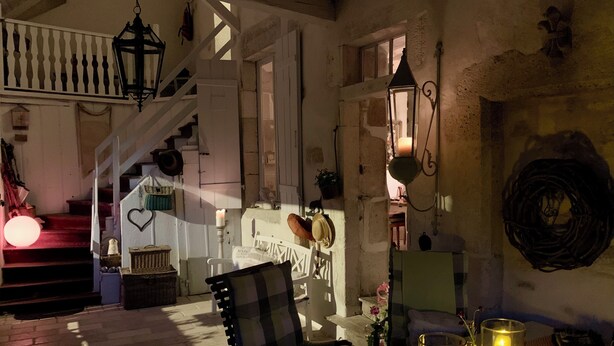 A cozy room with a wooden staircase, a dining table with candles, and a chair.