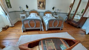 A bedroom with two beds, a wooden coffee table with books, and a mirror.