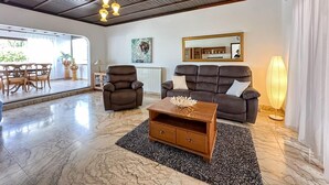 Amplia sala de estar con techo de madera, un sofá de cuero, una mesa de centro de madera y un gran ventanal con vistas.