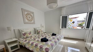 Un dormitorio moderno con una cama grande, una mesita de noche y un ventanal con vistas a zonas verdes.