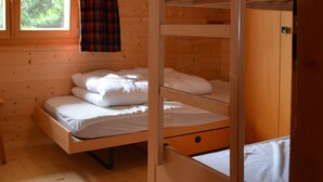 A wooden cabin room with a bunk bed, a window with curtains, and a wooden wardrobe. - Charming apartment facing south, overlooking the Cervin. Val d'Anniviers (Saint-Luc)