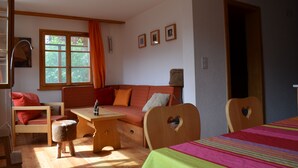 A cozy room with a wooden sofa, a small table, and a bed with a colorful striped bedspread. - Charming apartment facing south, overlooking the Cervin. Val d'Anniviers (Saint-Luc)