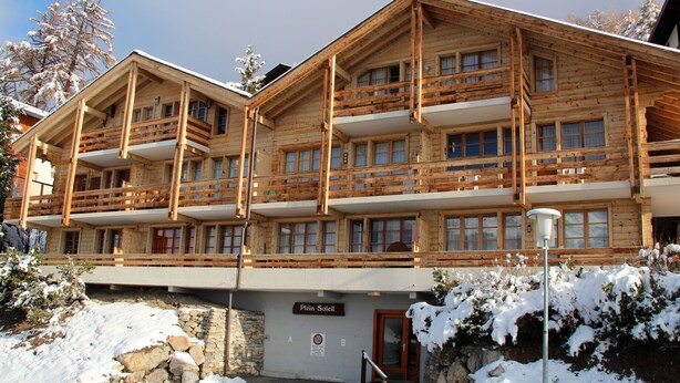 A wooden chalet with multiple balconies and a stone wall entrance. - Charming apartment facing south, overlooking the Cervin. Val d'Anniviers (Saint-Luc)