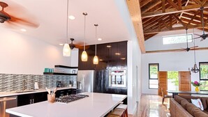 A modern kitchen with a large island, pendant lights, and a wooden ceiling. - Vivaro South House Luxury Villa Private Infinity Pool (West End)