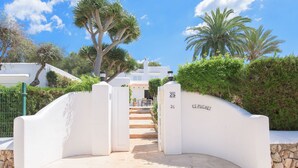 A white gate leading to a building with a stone wall and a palm tree in the background. - Beautiful villa with pool and garden,a/c, quiet location,  beach 200 mt (Cala Serena)