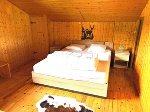 A wooden-paneled bedroom with a bed, two bedside tables, and a wall mural.