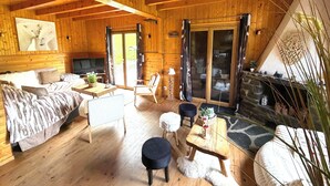 A wooden cabin interior with a sofa, chairs, a TV, a fireplace, and a dining area. - La Clusaz skiing and biking (La Clusaz)