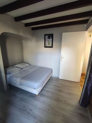 A bedroom with a bed, a door, and a framed picture on the wall.
