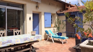 A patio with a table and chairs, a blue door, and a potted plant.