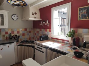 A kitchen with a gas stove, a microwave, a sink, and a window with a view of the outside. - Quiet house not overlooked, 30 m2 terrace 200 meters from the ramparts  (Avignon)