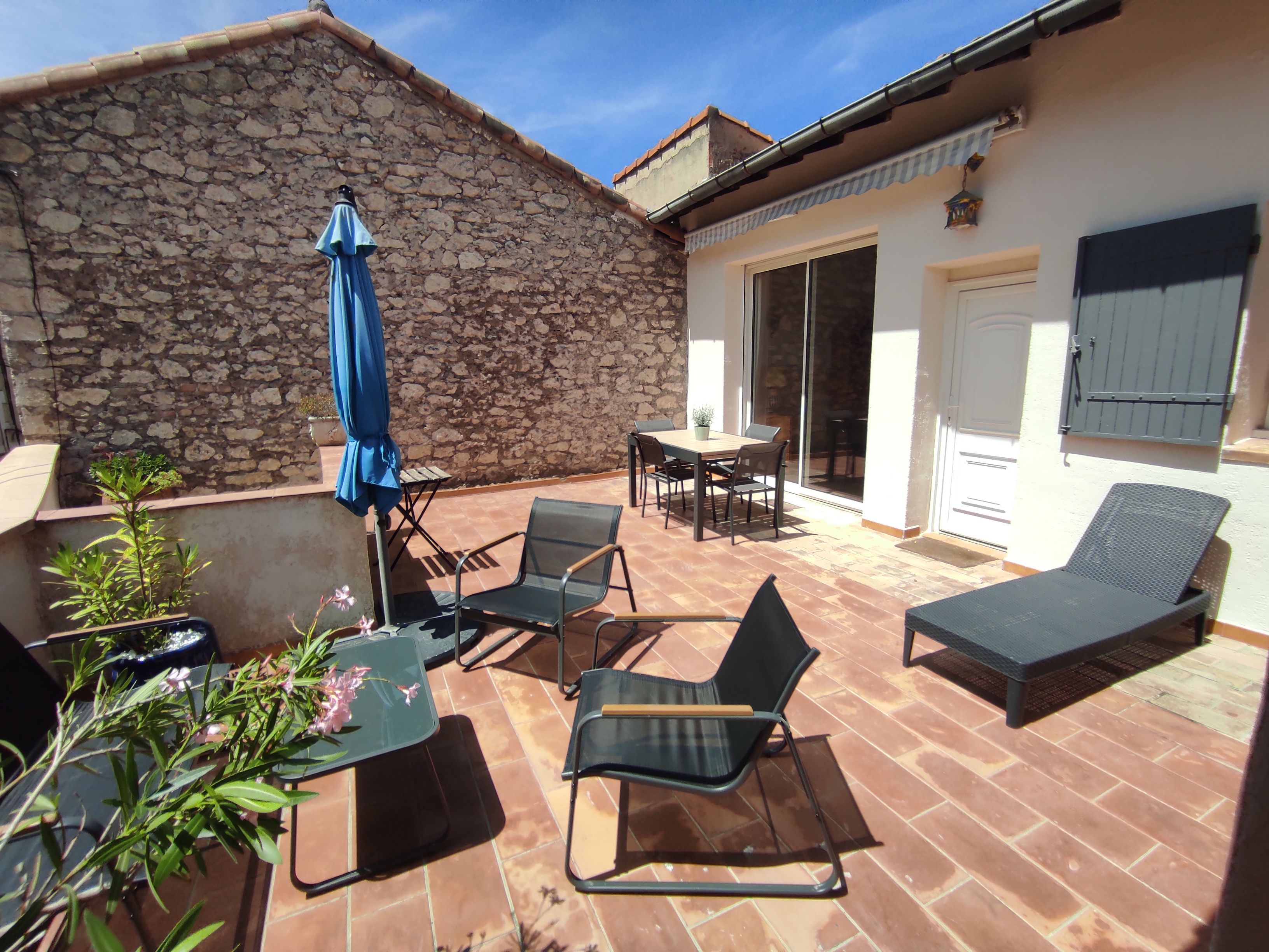 A patio with outdoor furniture, a stone wall, and a sliding glass door leading to an interior space.