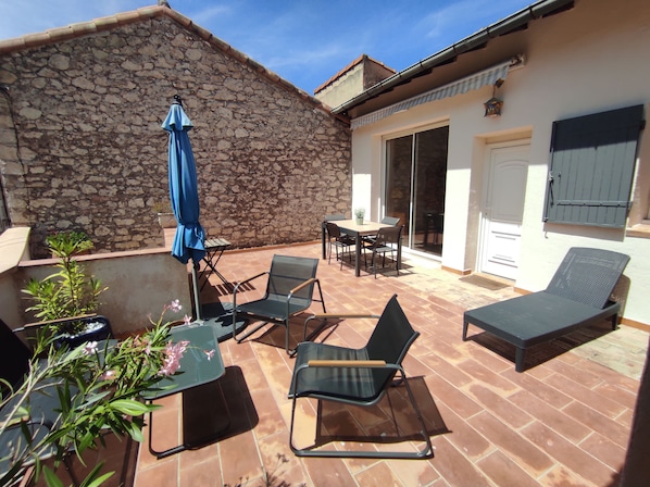 A patio with outdoor furniture, a stone wall, and a sliding glass door leading to an interior space.
