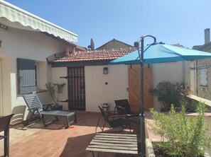 A patio with outdoor furniture, a blue umbrella, and a gate.