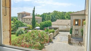 A courtyard with a building, a pergola, and a gate.