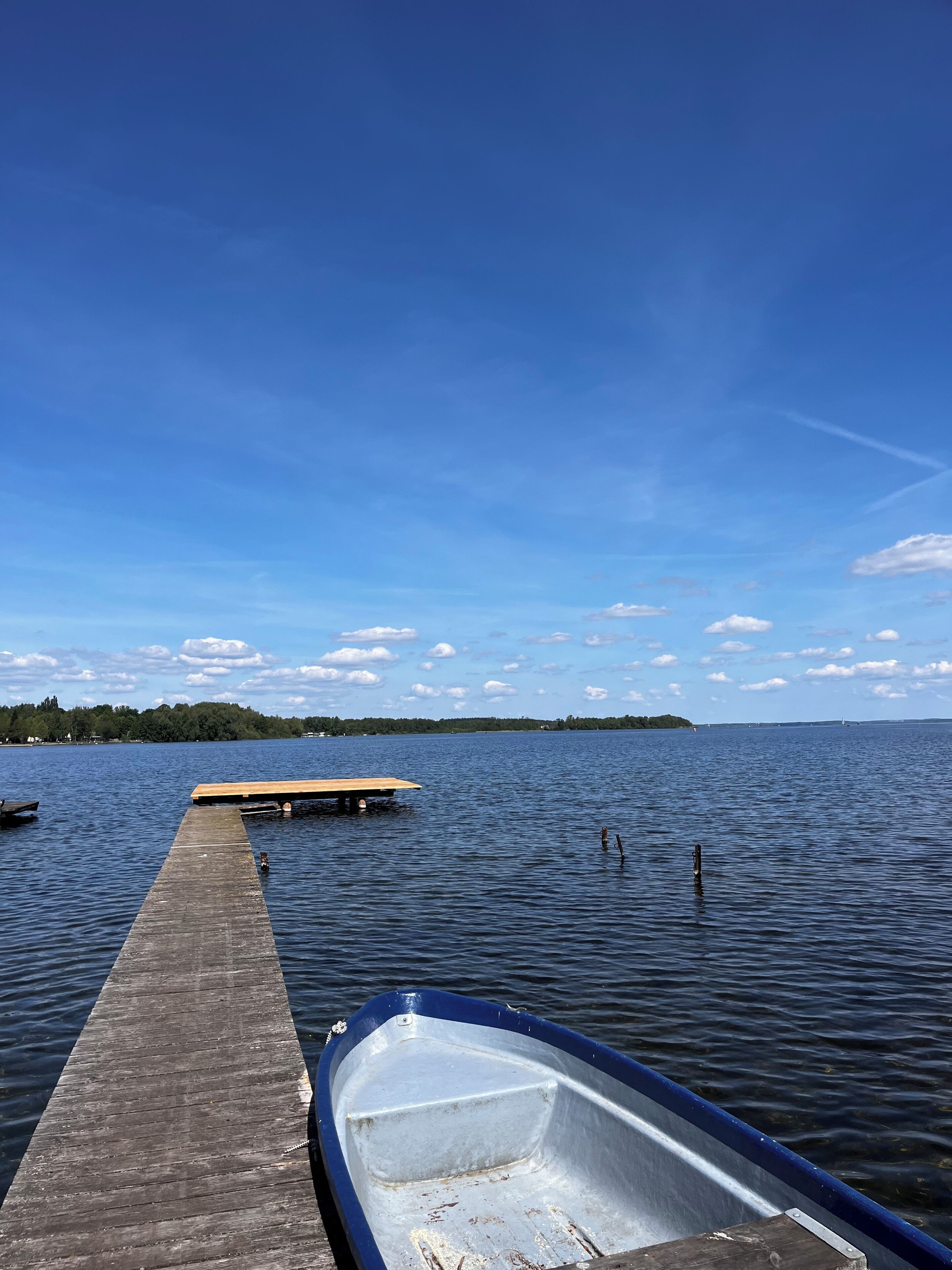 Une jetée en bois s’avance sur un lac paisible, et une petite embarcation est amarrée à son extrémité.