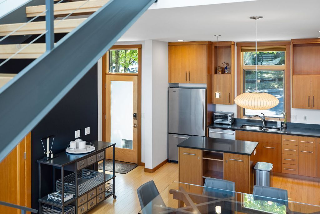 Eine moderne Küche mit Holzsärchen, einem Edelstahlkühlschrank und einem Glastisch.