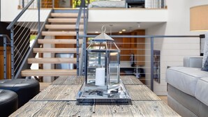 A modern living room with a wooden coffee table, a glass lantern, and a staircase leading to an upper level. - River Views! Contemporary Condo Centrally Located Walk To Restaurants/Breweries (Hood River)
