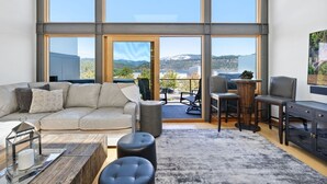 A spacious living room with a large window, a sofa, a coffee table, and a view of a mountainous landscape. - River Views! Contemporary Condo Centrally Located Walk To Restaurants/Breweries (Hood River)