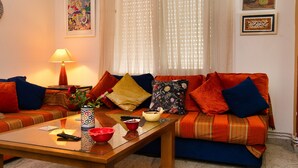 Un salon avec un canapé, une table basse, une lampe et des œuvres d’art accrochées aux murs.