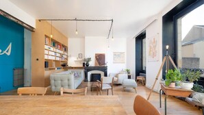 A modern living room with a fireplace, a bookshelf, and a dining area.