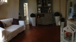 Un salon avec un canapé blanc, un meuble en bois et une vitrine en verre contenant des fleurs.