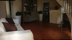 Un salon avec un canapé, un meuble et une petite table sur laquelle se trouve une lampe.