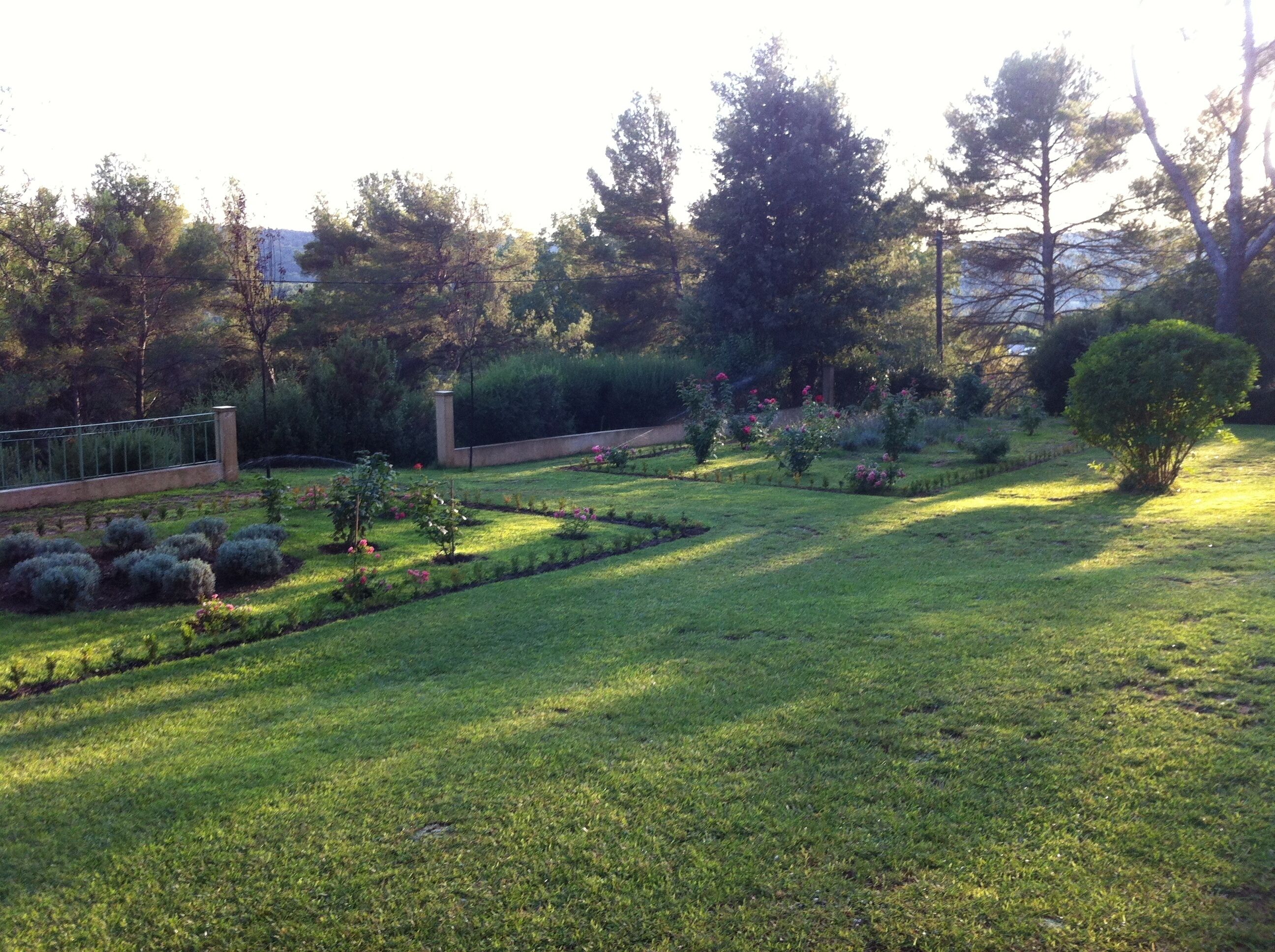A well-maintained garden with various plants and trees, a clear pathway, and a fence.