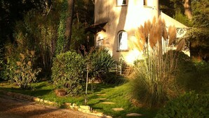 Un bâtiment rustique en pierre, entouré d’une végétation luxuriante et d’arbres.