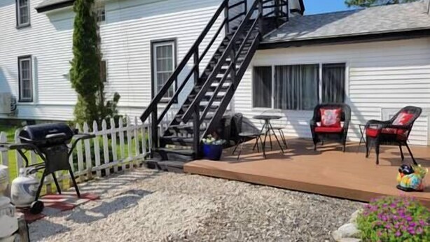 A house with a front deck, a staircase, outdoor furniture, and a barbecue grill. - The Nest - one bed apartment (Searsport)