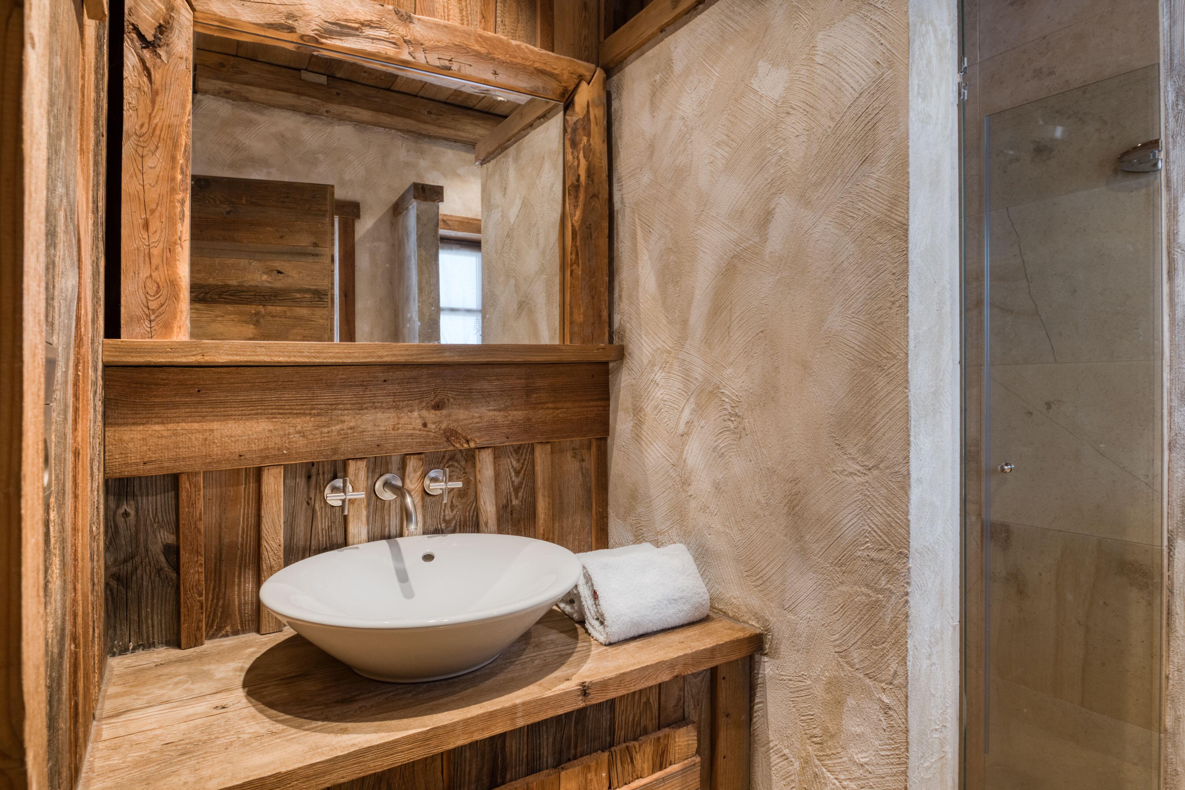 A wooden vanity with a large bowl sink and a mirror above it.