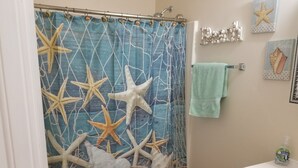A bathroom with a blue shower curtain decorated with starfish and seashells, a white sink, and a green towel hanging on the wall. -  40 ft to the ocean 4 bd/3 bath ocean view beach house sleeps  (Myrtle Beach)