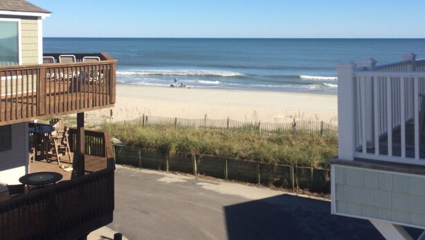 A beach view from a balcony with a wooden deck, a white railing, and a clear blue sky. -  40 ft to the ocean 4 bd/3 bath ocean view beach house sleeps  (Myrtle Beach)