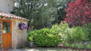 A stone building with a reception area, surrounded by a gravel driveway and various plants and shrubs.