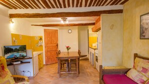 A compact living space with a dining area, a kitchenette, a TV, and a bed.