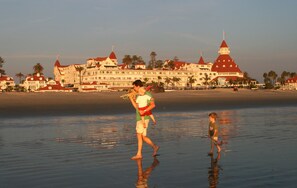 A beachfront hotel with multiple red-roofed buildings, palm trees, and a sandy beach.