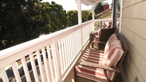 Ein überdachter Balkon mit Korbmöbeln und einem gestreiften Kissen.