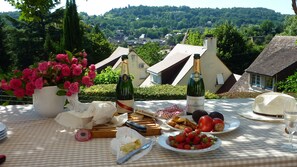Ein Tisch ist reichhaltig mit Speisen und Getränken gedeckt und bietet Blick auf ein Dorf mit Häusern und Grünflächen.