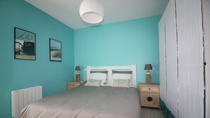 A bedroom with a bed, nightstands, a white headboard, and a window with white curtains. - House Bungalow 8p. any comfort near center and beaches, closed garden. St Denis (Saint-Denis-D'oléron)