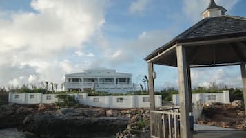 A coastal property with a large white house, a gazebo, and a rocky shoreline.