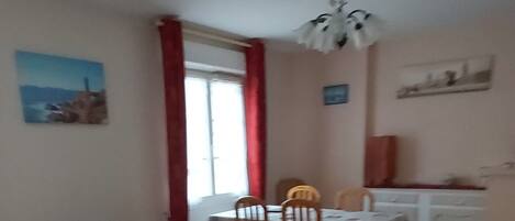 A living room with a red and white sofa, a dining table, and a kitchen area in the background.