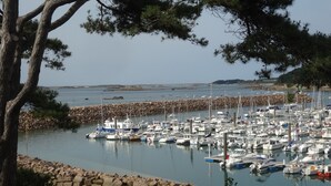 A marina with numerous boats docked, surrounded by a stone breakwater and pine trees. - Comfortable apartment, close to Perros-Guirec and Ploumanac'h beaches (Perros-Guirec)
