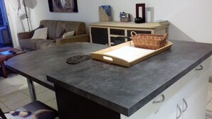 Una encimera de cocina con una cesta tejida, una tabla de cortar y una bandeja de metal.